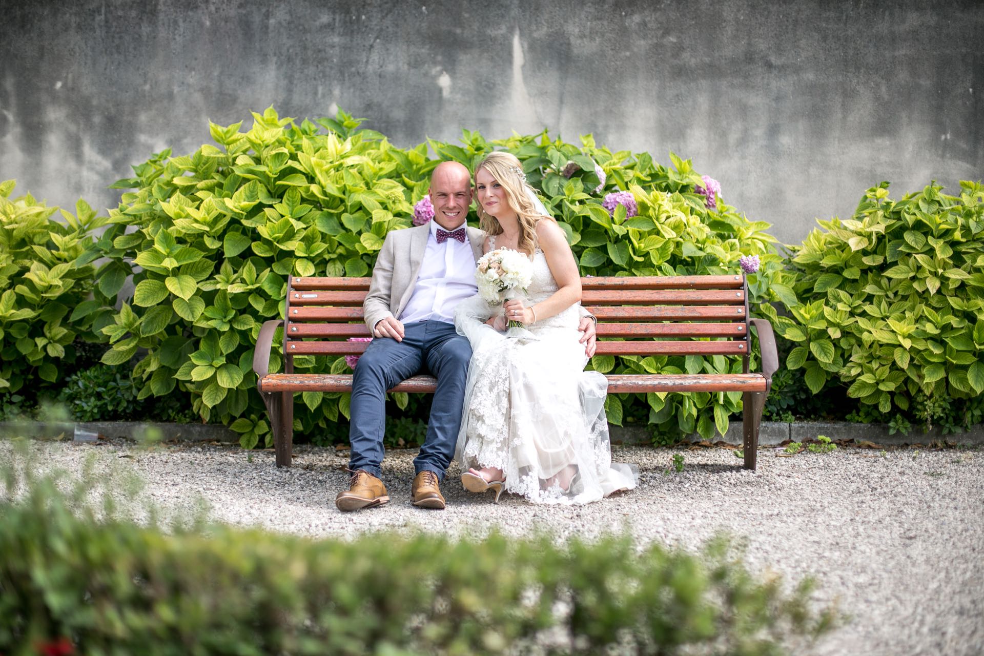Couple sitting on a bench in Malcesine. Flowers behind them.